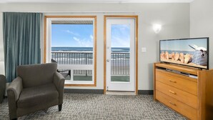 Una habitación de hotel con balcón, televisión y cómoda de madera.