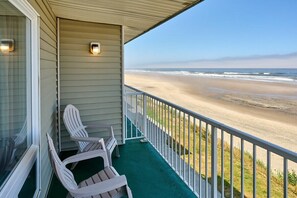 A balcony with a view of the beach, white chairs, and a railing. - Beachfront Suite - Ocean Views - Heated Pool & Hot Tub! (Lincoln City)