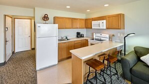 A compact kitchen with wooden cabinets, a white refrigerator, a microwave, and a coffee maker.