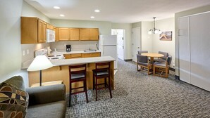 A compact kitchen with wooden cabinets, a white refrigerator, and a small dining area with a table and chairs.