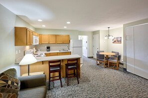 Una cocina compacta con armarios de madera, un refrigerador blanco y un pequeño comedor con mesa y sillas.