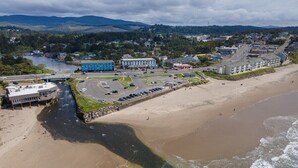 Luftaufnahme einer Küstenstadt mit Strand, Parkplatz und Gebäuden, darunter ein blaues Hotel.