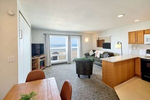 A compact living space with a dining area, kitchenette, and a balcony with a view.