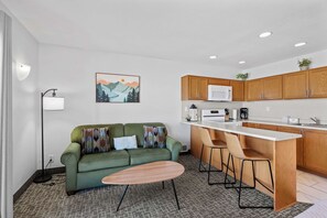 A modern kitchen with wooden cabinets, a white countertop, and a built-in microwave. - Oceanfront Suite - Sleeps Six - Full Kitchen - Pool and Hot Tub! (Lincoln City)