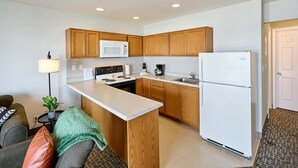Une cuisine de taille réduite, avec des meubles en bois, un réfrigérateur blanc, un four à micro-ondes et une cuisinière.