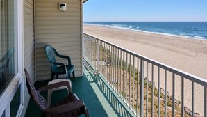 Un balcon donnant sur la plage, une fenêtre et deux chaises.