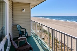 Un balcón con vistas a la playa, una ventana y dos sillas.