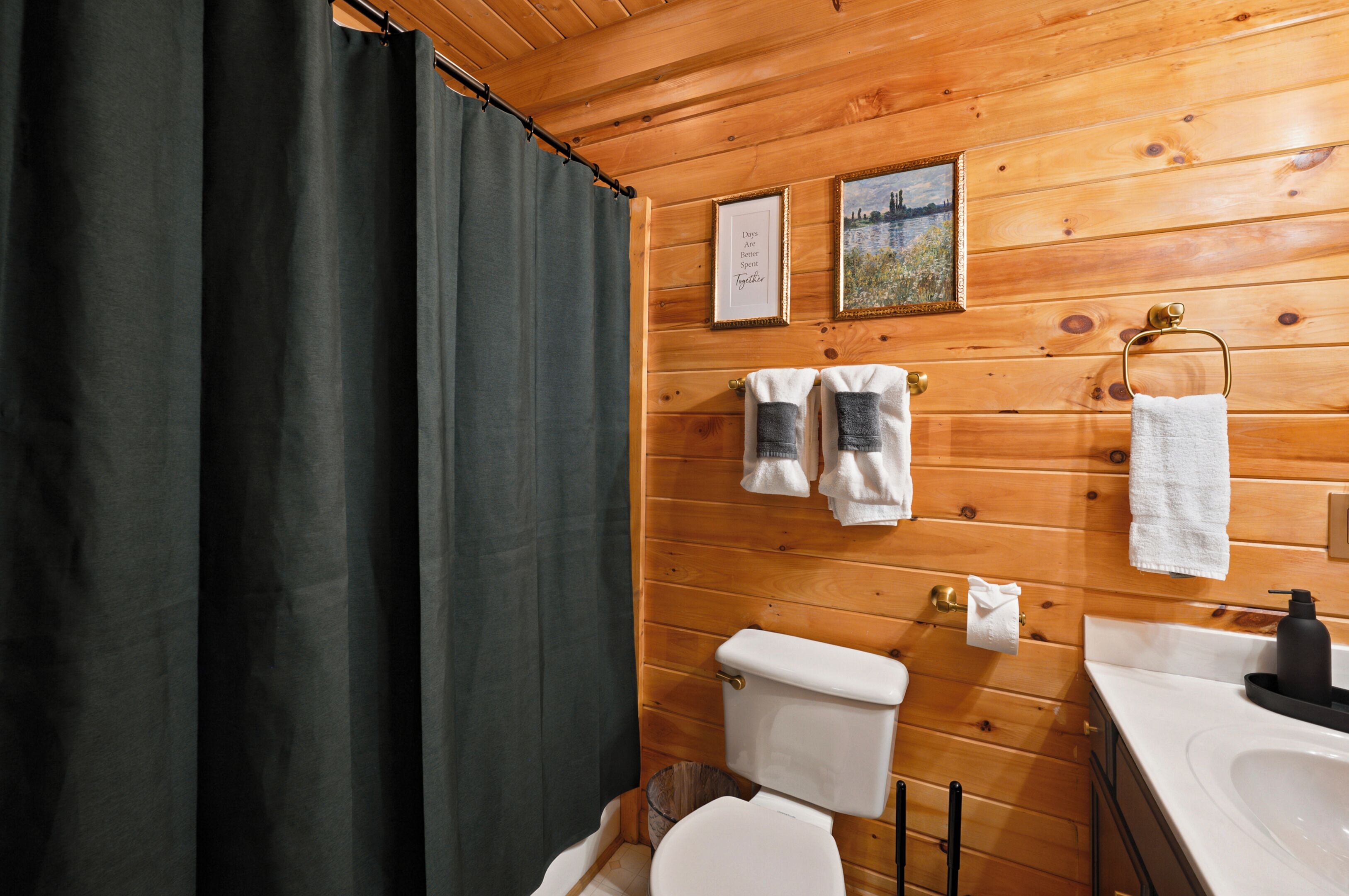 A wooden-paneled bathroom with a toilet, sink, and shower curtain.