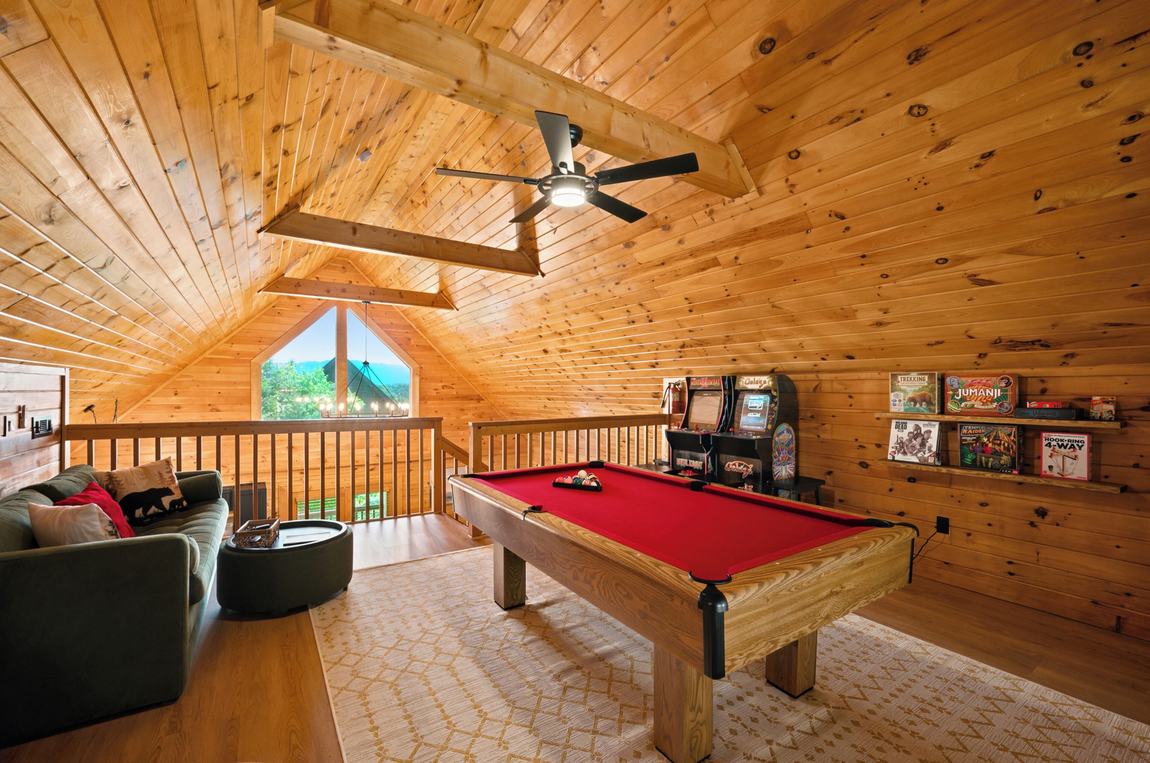 A cozy wooden room with a pool table, a sofa, and a ceiling fan.