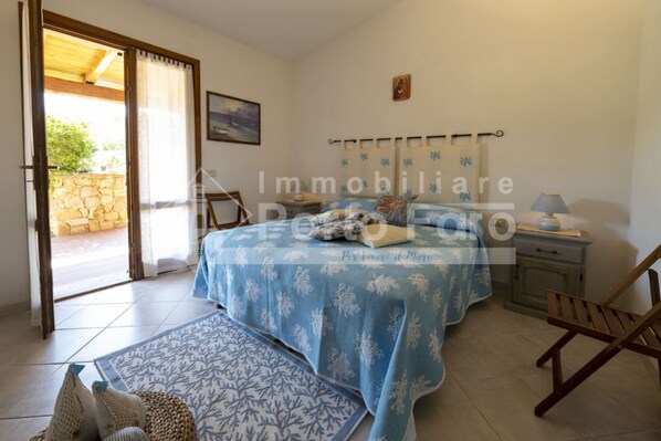 Una camera da letto con un letto, un comodino, una lampada, una sedia e vista sull'esterno.