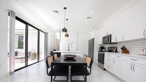 Une cuisine moderne avec des meubles blancs, une table à manger noire et une grande fenêtre.