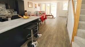 Une cuisine moderne dotée d’un îlot central, de tabourets de bar et d’un coin repas avec une nappe rouge.