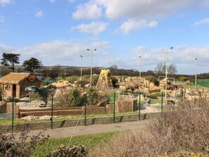 Un'esposizione di dinosauri con un edificio in legno con la scritta "Dino's Island" e un recinto.