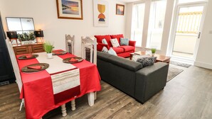 Un salon moderne avec un coin repas, comprenant une table à manger rouge, un canapé gris et un divan rouge.