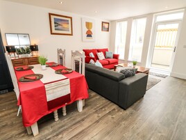 Una sala moderna con comedor, que incluye una mesa de comedor roja, un sofá gris y un sofá rojo.