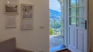 A room with a view of a hillside town through a glass door, framed artwork on the wall, and a chair. - Blueberry - Charming apartment, with panoramic terrace with a view over Levanto (Montale)