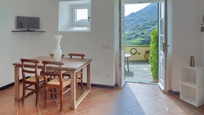 A dining area with a wooden table and chairs, a small window, and a view of a mountainous landscape through an open door. - Blueberry - Charming apartment, with panoramic terrace with a view over Levanto (Montale)