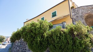 A building with a stone wall and a yellow facade, featuring a small window and a green door. - Blueberry - Charming apartment, with panoramic terrace with a view over Levanto (Montale)