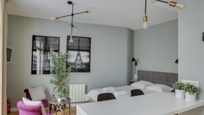 A modern hotel room with a large bed, a dining area, and a seating area with a purple chair. - Charming studio in the heart of Paris for 2 people (Paris)
