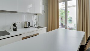 A modern kitchen with white cabinets, a built-in oven, a kettle, and a sink. - Charming studio in the heart of Paris for 2 people (Paris)