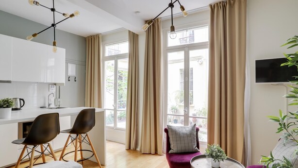 A modern hotel room with a kitchen, dining area, and seating space. - Charming studio in the heart of Paris for 2 people (Paris)