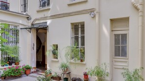 A courtyard with potted plants and a staircase leading to an upper floor. - Charming studio in the heart of Paris for 2 people (Paris)