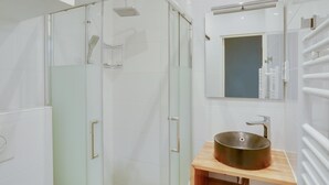 A modern bathroom with a glass-enclosed shower, a wooden vanity with a vessel sink, and a mirror above the sink. - Charming studio in the heart of Paris for 2 people (Paris)