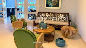 A living room with a green armchair, a wooden coffee table, a patterned sofa, and a decorative vase. - PARADISE VILLA  CHEF+FOOD GOLF POOL BBQ KING BEDS (Juan Dolio)