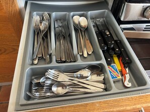 Un cajón con compartimentos que contiene diversos utensilios de cocina, como tenedores, cucharas y cuchillos.
