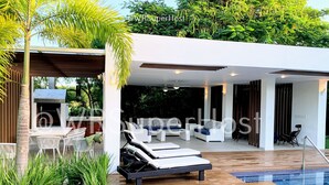 A modern outdoor living area with a pool, lounge chairs, and a barbecue. - PARADISE VILLA  CHEF+FOOD GOLF POOL BBQ KING BEDS (Juan Dolio)
