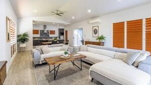A spacious living room with a sofa set, a coffee table, and a view of the kitchen.
