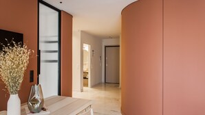 Un interior moderno con una pared curva, una mesa de madera con un florero y vistas a un baño.