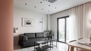 Una sala de estar moderna con un sofá gris, una mesa de centro de vidrio y un comedor con una mesa y sillas de madera.
