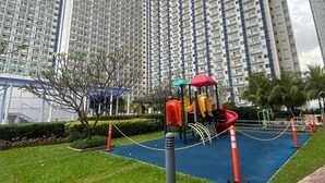 Ein Wohngebiet mit Hochhauswohnungen, einem Spielplatz mit bunten Geräten und einer gepflegten Grünfläche.