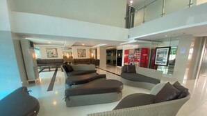 Eine großzügige Lobby mit modernen Sitzgelegenheiten, einer hohen Decke und einer sichtbaren Treppe.