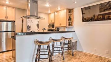 A modern kitchen with wooden cabinets, stainless steel appliances, and a central island with bar stools.