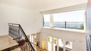 En trappe med sorte gelændere fører op til en balkon med havudsigt.