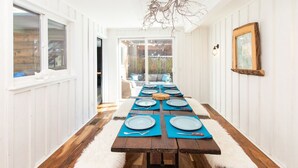 A long wooden table set for a meal with blue placemats and plates, white furry rugs, and a rustic wooden picture frame on the wall. - Multi-Generation retreat! Pet friendly w/ fenced yard. 5 min to lake & trails. (Truckee)