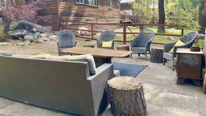 A log cabin with a patio area featuring wicker furniture and a wooden table. - Multi-Generation retreat! Pet friendly w/ fenced yard. 5 min to lake & trails. (Truckee)