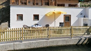 A white building with a balcony, a table with chairs, and a yellow umbrella. - Vacation home Villa klein Venedig, 60sqm, 2 bedrooms, balcony, terrace, WLAN (Siegsdorf)