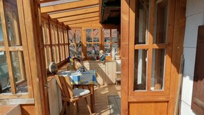 A wooden deck with a table and chairs, large windows, and a view of the surrounding area. - Vacation home Villa klein Venedig, 60sqm, 2 bedrooms, balcony, terrace, WLAN (Siegsdorf)