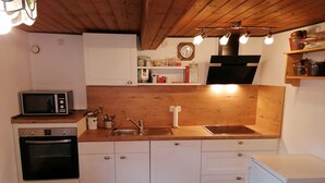A compact kitchen with a microwave, oven, sink, and two white chairs. - Vacation home Villa klein Venedig, 60sqm, 2 bedrooms, balcony, terrace, WLAN (Siegsdorf)