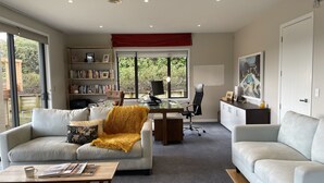 Ein modernes Wohnzimmer mit zwei weißen Sofas, einem Couchtisch, einem Bücherregal und einem Schreibtisch mit einem Computer.