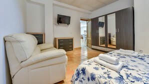 A bedroom with a bed, a sofa, a wardrobe, a TV, and a bathroom visible through an open door. - Villa for rent in Calpe AZORIN for 6 pax, with private pool. (Calpe)