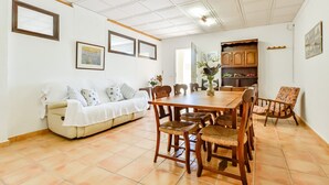 A dining area with a wooden table and chairs, a white sofa with patterned cushions, and framed artwork on the walls. - Villa for rent in Calpe AZORIN for 6 pax, with private pool. (Calpe)