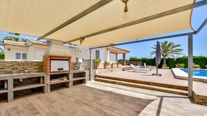 An outdoor patio with a barbecue area, poolside seating, and a covered section. - Villa for rent in Calpe AZORIN for 6 pax, with private pool. (Calpe)