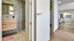 Un bagno moderno con cabina doccia in vetro, un mobile bagno in legno e un tappeto rosa.