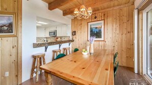 Un comedor de madera con una mesa grande, sillas y una araña.