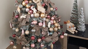 Un sapin de Noël décoré de guirlandes et de rubans, une étoile au sommet et une petite figurine de renne.