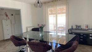Une cuisine moderne avec une table à manger en verre, quatre chaises violettes, un réfrigérateur blanc et un flamant rose décoratif.
